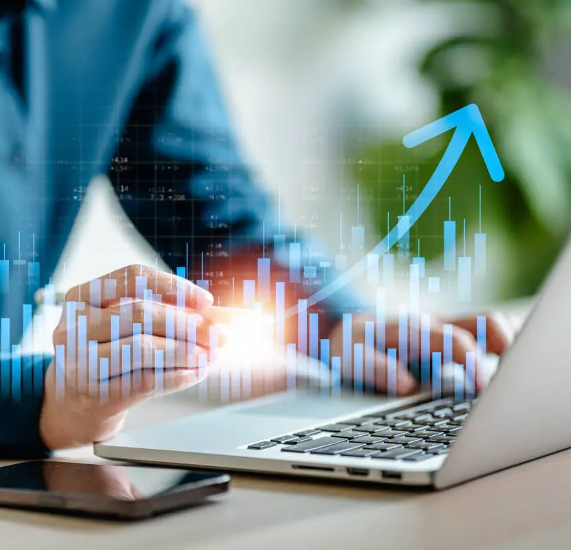 Laptop with rising financial charts overlay